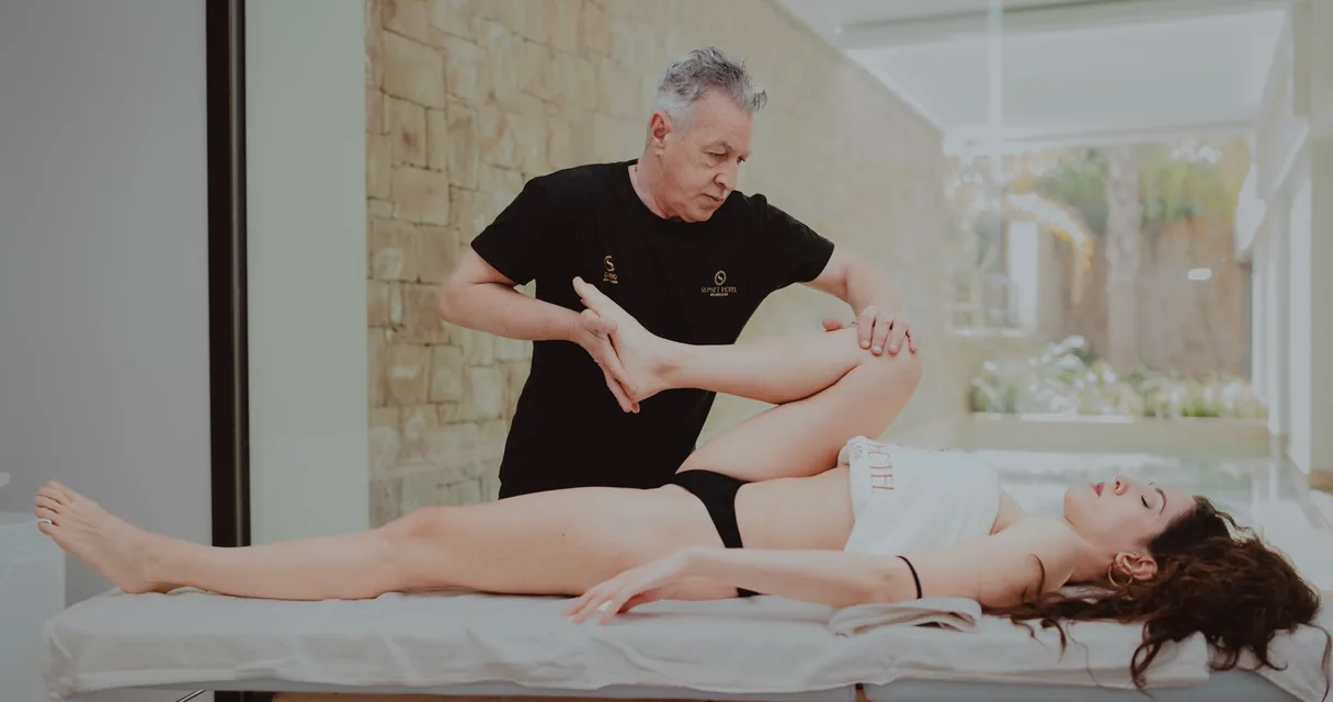 Fisioterapeuta mobilizando a articulação de uma paciente deitada na maca de uma clínica